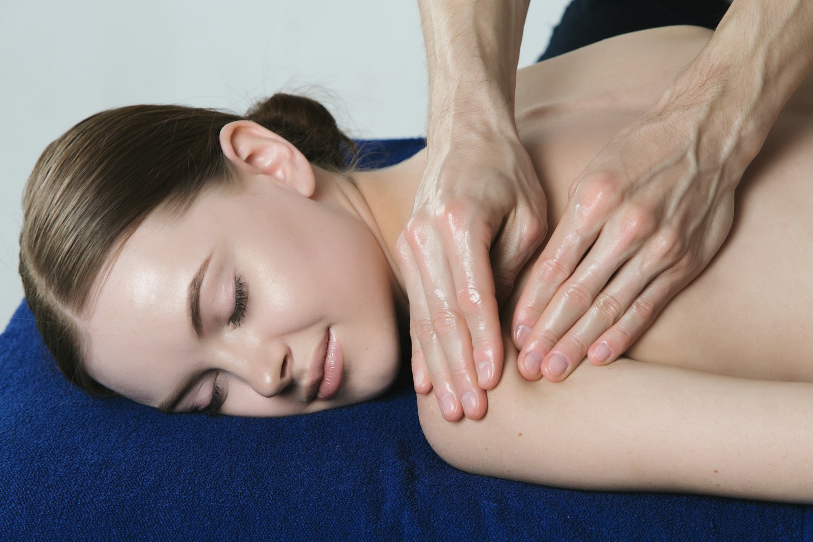 A client receiving a shoulder and back massage on a treatment table