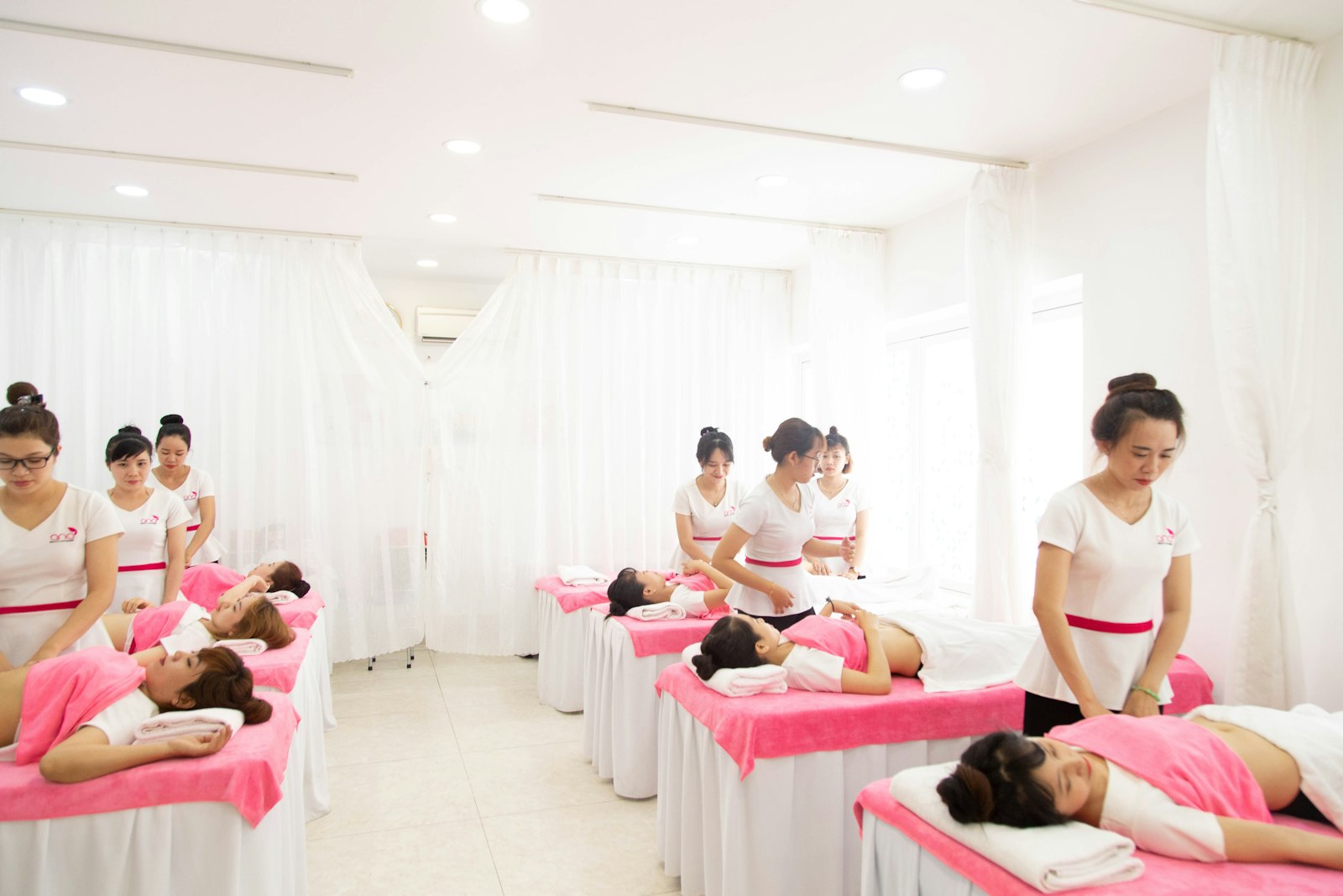 Beauty treatment beds lined up in a bright white treatment room
